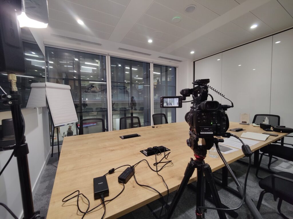A camera on a tripod in an empty meeting room at the end of a shoot, when the cards are backed up.